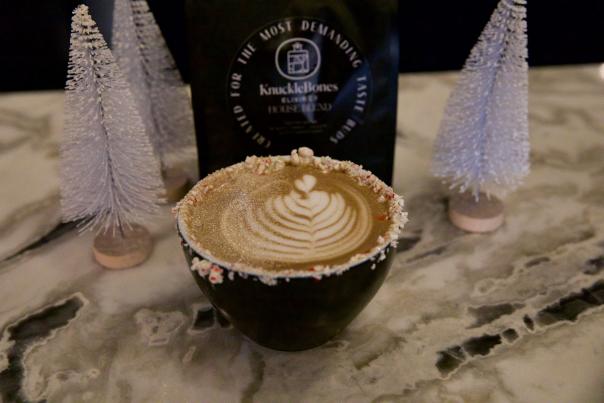 Coffee in mug next to mini artificial Christmas trees