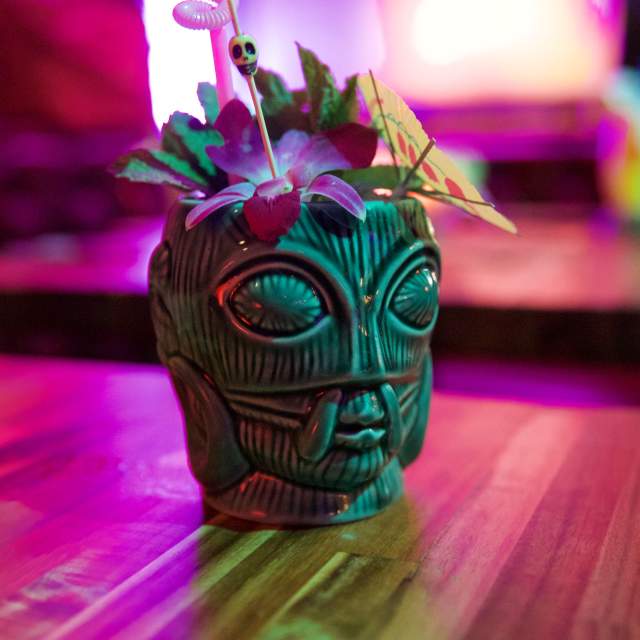 Tiki themed cocktail shot in colorful light.