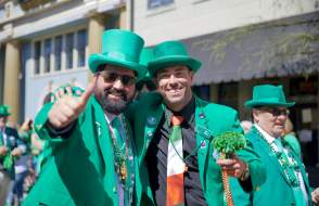 Two men wearing green and posing for a picture at a St. Patrick's Day parade