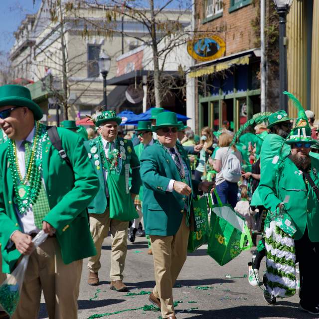 Group of men wearing green walking down Dauphin Street.