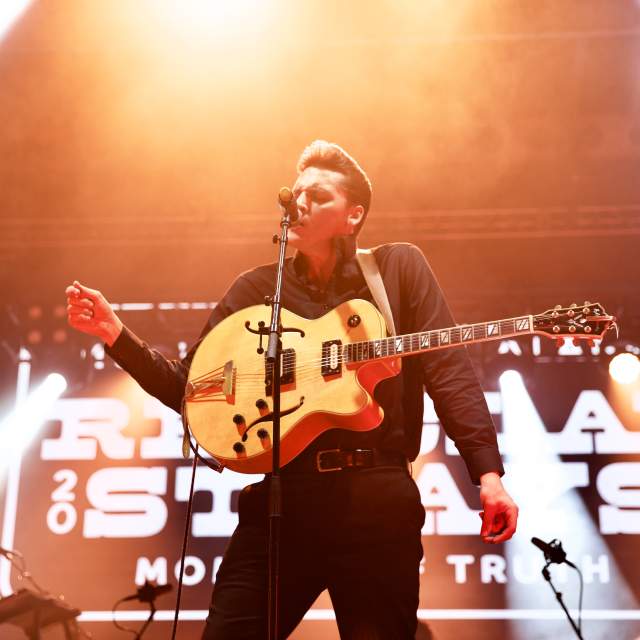 Man singing into a microphone holding a guitar