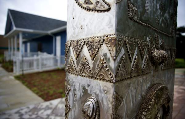 steel sculpture in front of blue building with white trim