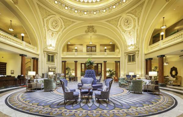 Ornate historical lobby with seating in the middle and a round skylight
