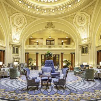 Ornate historical lobby with seating in the middle and a round skylight