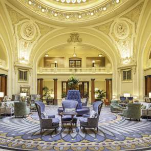 Ornate historical lobby with seating in the middle and a round skylight