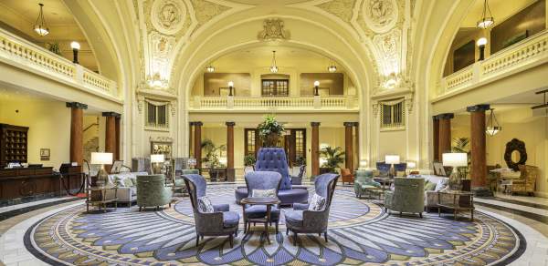 Ornate historical lobby with seating in the middle and a round skylight
