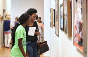 two people looking at art hanging on the wall
