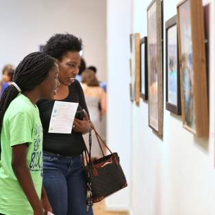two people looking at art hanging on the wall