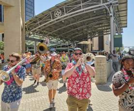 Men play horns leading a group of people celebrating