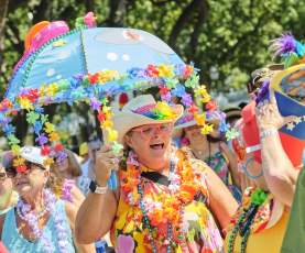 A lady celebrates dressed in tropical clothes with a tropical umbrella