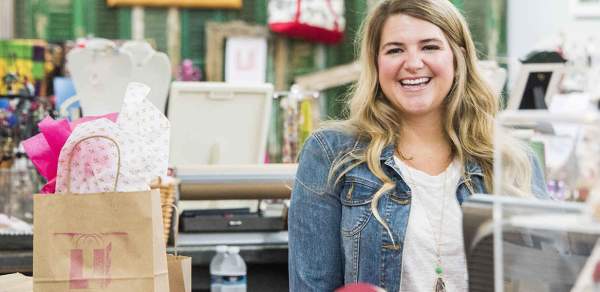 blonde woman smiling in front of merchandise in mobile alabama