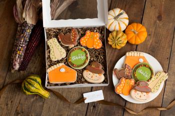 Box and plate stuffed with decorated cookies on top of a table.