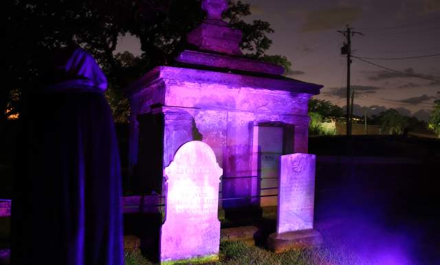 Graveyard at night lit with Mardi Gras purple lights