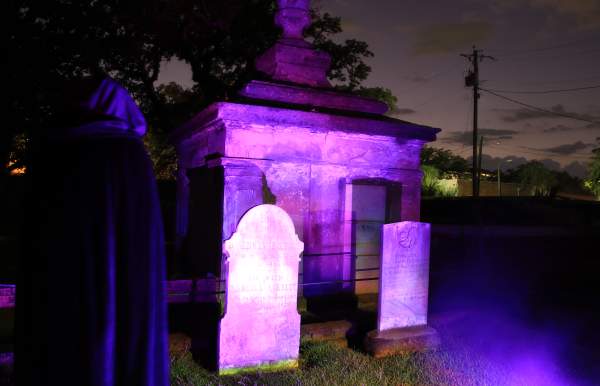 Graveyard at night lit with Mardi Gras purple lights