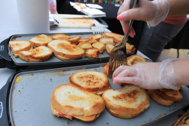 Two hands are flipping a grilled cheese sandwich over using a spatula.