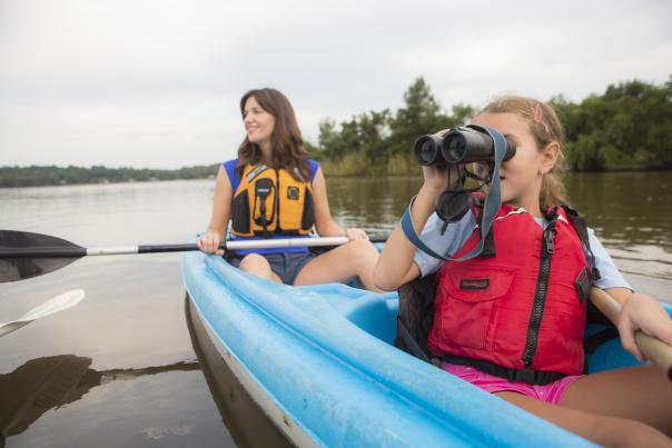 woman with oar and daughter with binoculars in a blue kayak