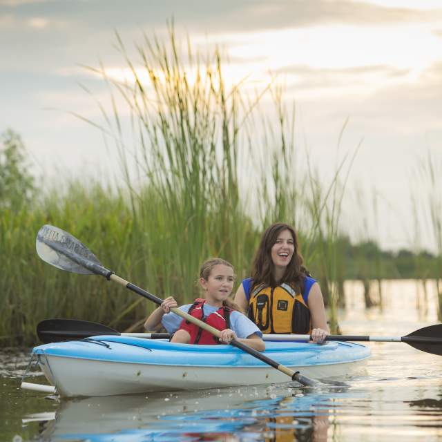 One adult and one child paddling on a kayak.
