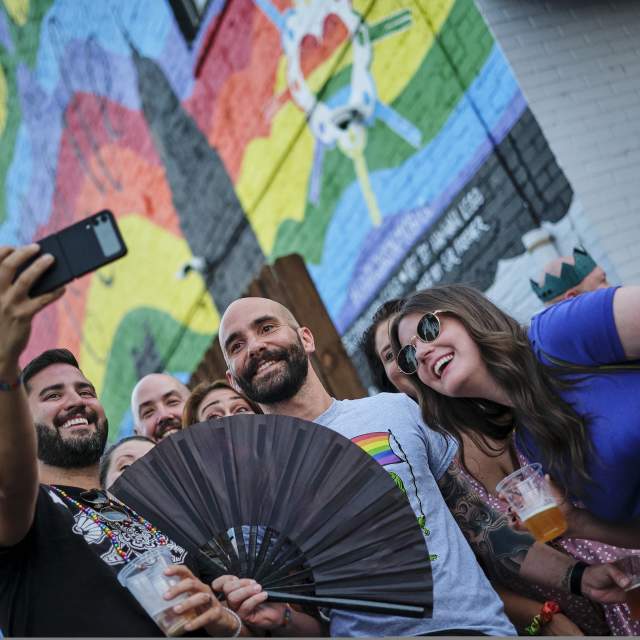 group of people taking a selfie in front of a rainbow mural