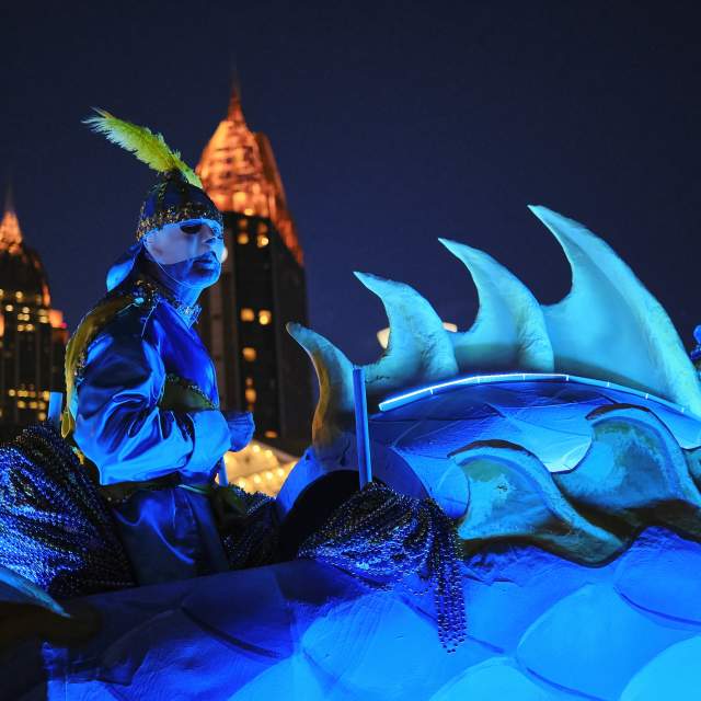 Masked man riding Mardi Gras float