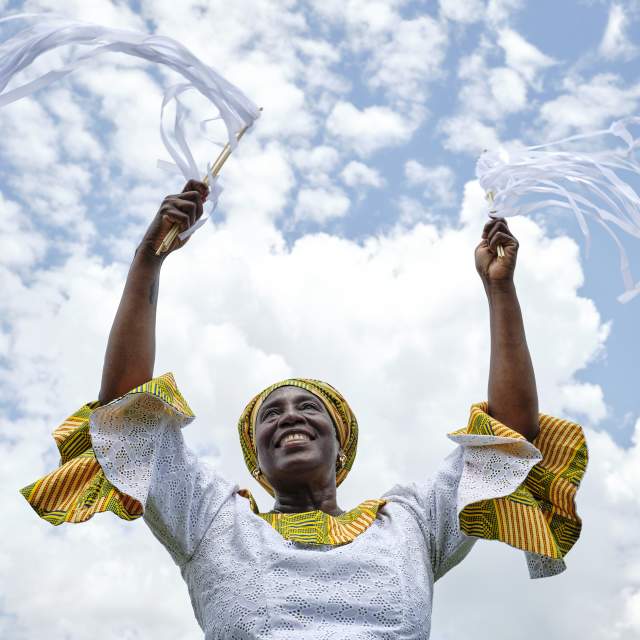 woman in white and yellow dress with arms raised to the sky