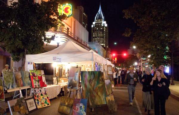 people walking down the street at night looking at art