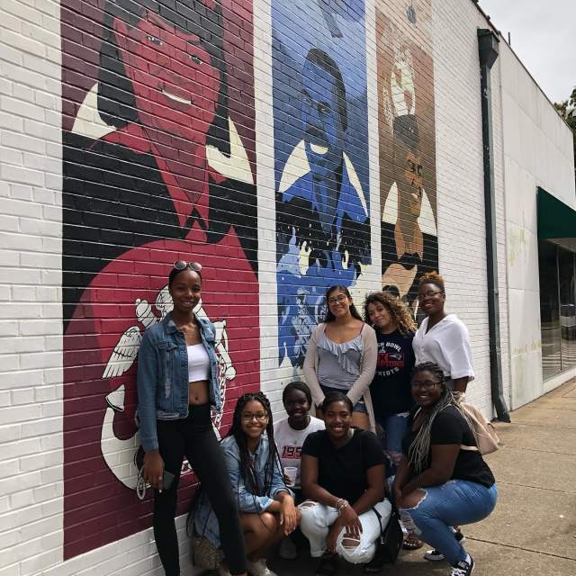 group of people on the sidewalk in front of a mural