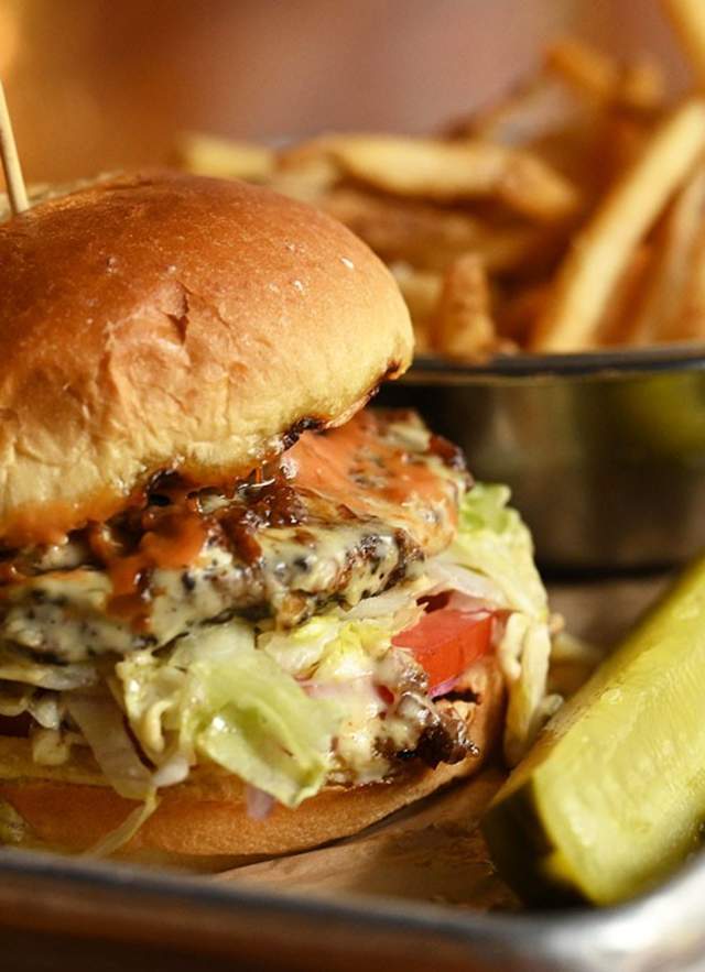 Close shot of burger, fries and a pickle spear