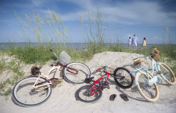 three bicycles laying on a sand dune on the beach