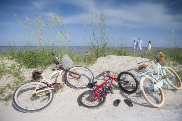 three bicycles laying on a sand dune on the beach