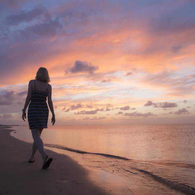Woman walking along the shore on Dauphin Island's beach