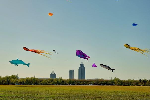 colorful kites flying with the city scape in the background
