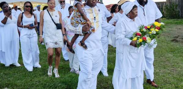 Group of African Americans in white clothing holding flowers and marching
