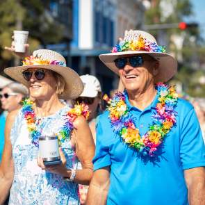Middle-aged couple wearing bold blue clothes, hats and leis