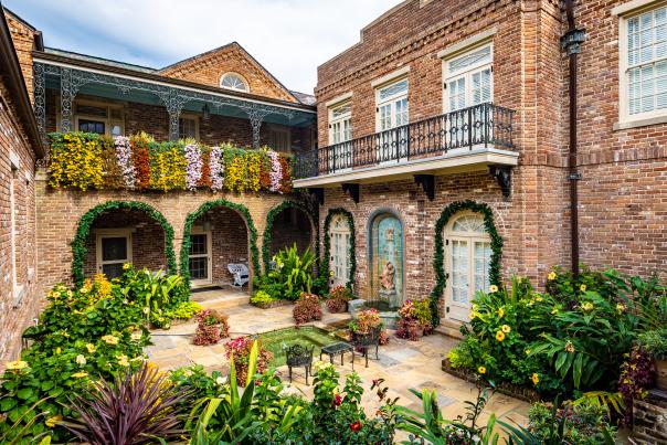 Cascading mums hanging from wall and greenery surrounding buildings in a courtyard at Bellingrath Gardens & Home