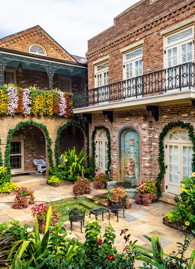 Cascading mums hanging from wall and greenery surrounding buildings in a courtyard at Bellingrath Gardens & Home