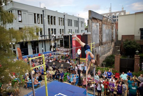 Pole vaulter clears the pole while a crowd watches from the street