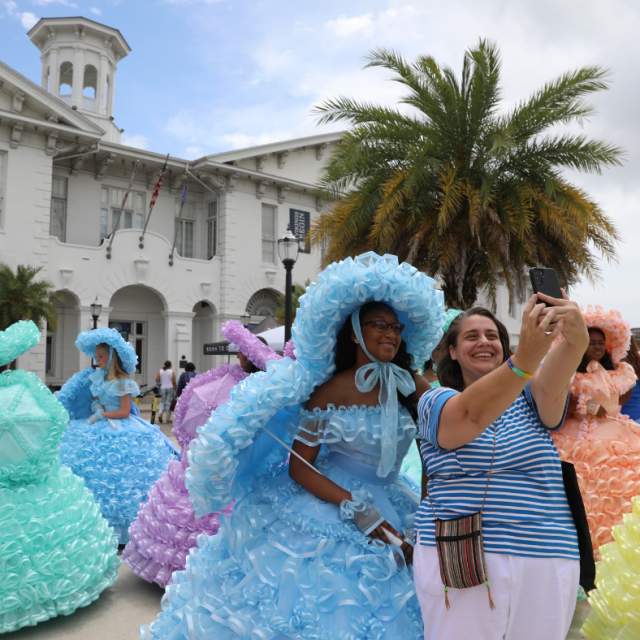 lady posing with an Azalea trail maid in front of the History Museum