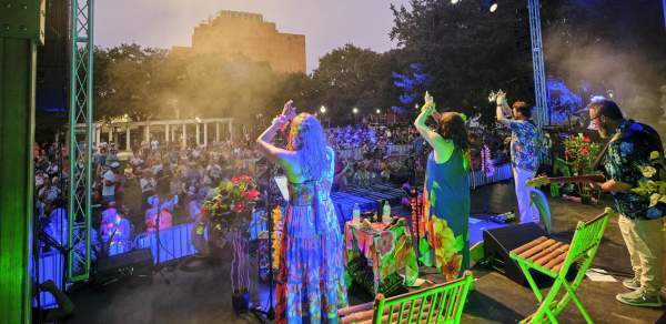 Women on stage clap as an audience cheers them on