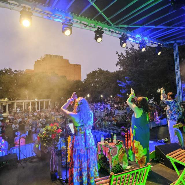 Women on stage clap as an audience cheers them on