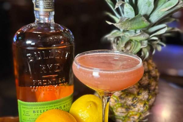 bottle of liquor, orange slices, mixed drink in a martini glass, pineapple