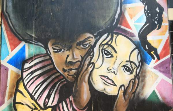 Mural of young Michael Jackson holding a mask of adult Michael Jackson