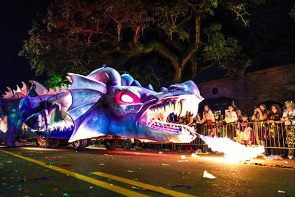 A purple Mardi Gras float shaped like a dragon blows fire during the parade