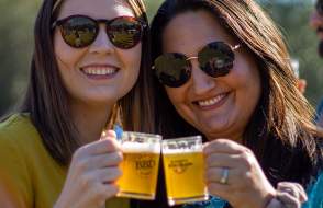 Two women making a toast with mugs of beer