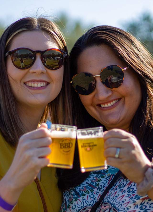Two women making a toast with mugs of beer