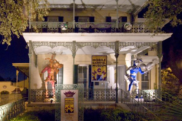 Historical, white house with iron columns and trim, two Mardi Gras Jesters on the porch