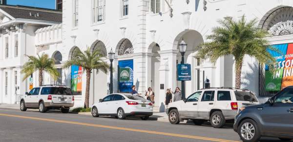 vehicles parked on the side of the road in front of a historic building