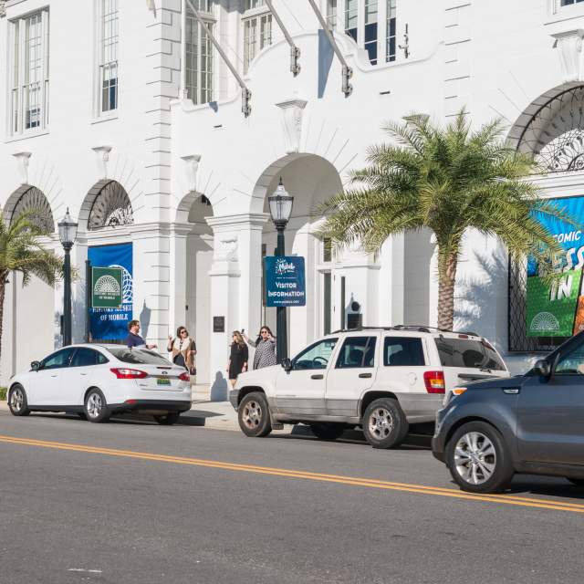 vehicles parked on the side of the road in front of a historic building