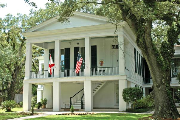 white two-story building with four columns and two flags