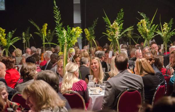 group of people smiling and talking while sitting at banquet tables
