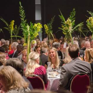 group of people smiling and talking while sitting at banquet tables